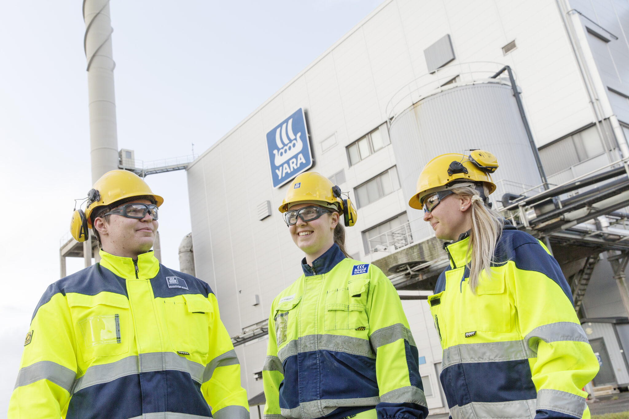 Kolme Yaran työntekijää seisoo Yaran tehtaan edessä.